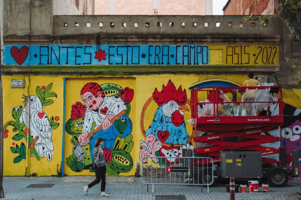 Una chica camina frente a un mural en el barrio del Poblenou.