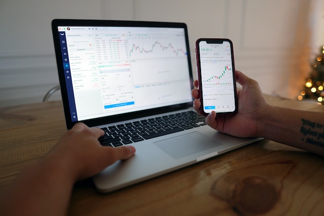 persona trabajando con un ordenador y un teléfono móvil
